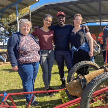 Three women and one man smile at the camera during an outreach event
