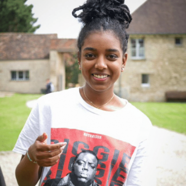 French youth build trust and confidence Black female youth smiles and reaches out to the camera